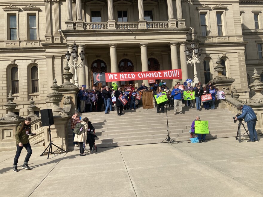 People on steps of state Capitol at 3-12-25 rally in support of modifying auto no fault law to restore access to long-term care benefits for catastrophically injured crash survivors