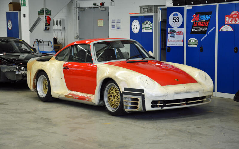 Red and white Porsche race car in a garage.